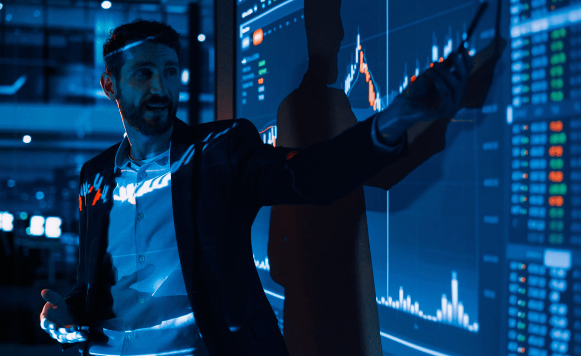 Trader apontando para um gráfico em uma tela
